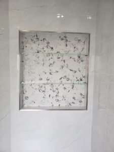 glass shelving in white marble shower