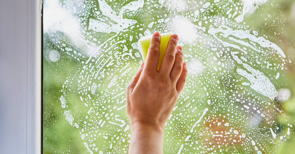 hand using sponge to gently clean custom glass window